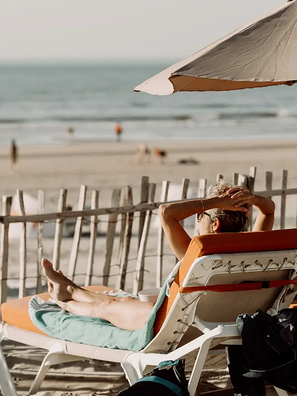 vrouw ligt op strandbedje naar zee te kijken